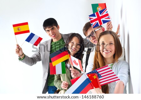 Group of cheerful happy students holding international flags and looking at camera leaning on white wall at campus. International education concept Royalty-Free Stock Photo #146188760