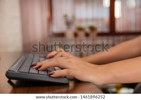 Woman writing a blog at home on a computer keyboard. Female hands on the keyboard, blurred background. Close up, selective focus