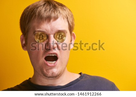Portrait of fat man with open mouth and bitcoins in eyes. Concept of digital cryptocurrency, mining, financial pyramid, invested money on yellow background
