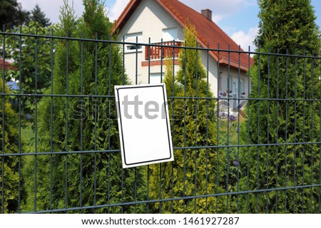 empty information plate on the fence against the background of a blurred house