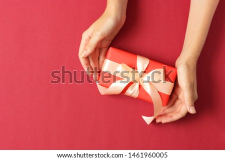 gift in female hands on a colored background top view.