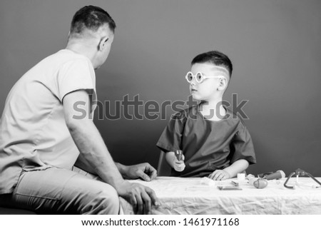 Boy cute child and his father doctor. Hospital worker. Health care. Medicine concept. Kid little doctor sit table medical tools. Illness treatment. Dad and son medical dynasty. Medical examination.