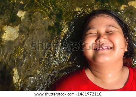 the girl is lying on the rocks and there is a river running through.He is doing hair spa