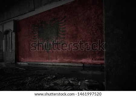 painted flag of albania on the dirty old wall in an abandoned ruined house. concept