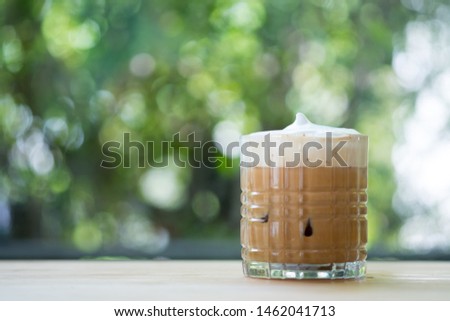 Iced cappuccino coffee with milk foam on top on wooden table