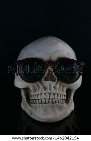 Skull wearing various differing styles of sunglasses against a black background