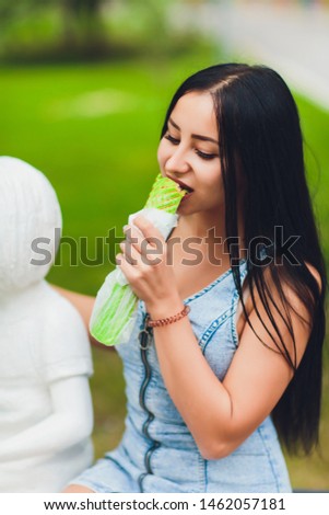 Pretty sunny girl holding juicy chicken shawarma on the nature. Close-up of fast food outdoors.