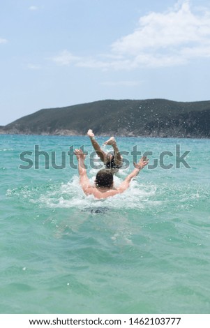 Father, playing with child, executing water jumps at the seaside