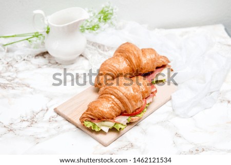 Sandwich croissants on a marble surface and wooden plate