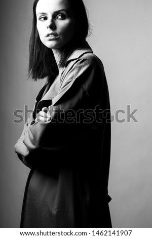 
beautiful young girl in a trench coat, black and white vertical photo