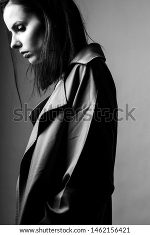 beautiful young girl in a trench coat, black and white vertical photo