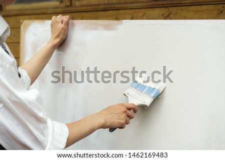 Female hand with brush paints a white sheet. Clear sheet. Place for text