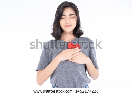 Portrait of beautiful Asian woman with appealing smile and holding heart shape love symbol with hands on chest with closed eyes and grateful gesture on face isolated over white background.  Royalty-Free Stock Photo #1462177226