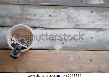 On the large plan photo there is a bucket with white putty and a construction paint spatula.