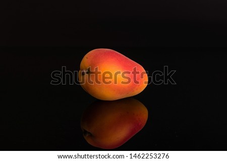 One whole fresh orange apricot isolated on black glass