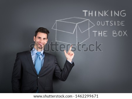 smiling businessman showing a drawing of think out of the box