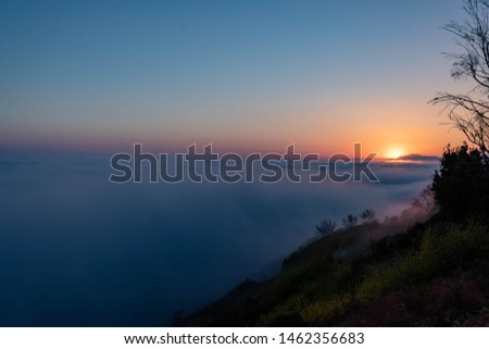 The spring sun is setting above the clouds along the central coast of California