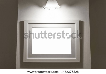 Blank picture lamp on white frame isolated on concrete background