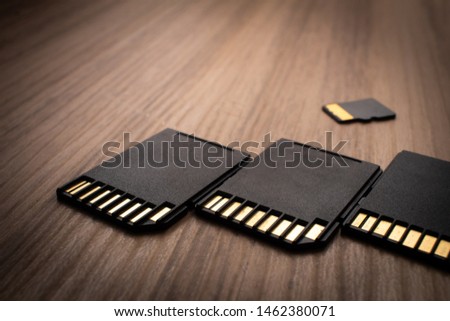 Micro sd card, technology products. Photograph of three adapters and a micro sd card on a wooden object.