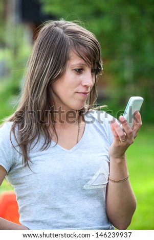 Young beautiful woman holding cell phone and looking at screen