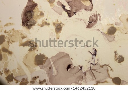 This is a photograph of an abstract biege, brown,purple and White abstract design created using nail polish