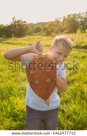 Closeup sunny portrait of cute happy young kid playing wooden toys outdoor in scenic summer sunset meadow background. Vertical color photography.