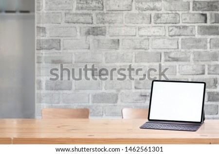 Mockup blank screen tablet with keyboard on wooden table.