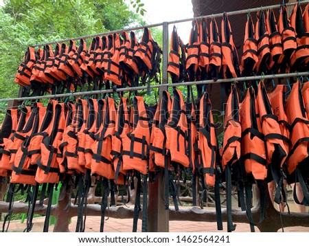 Orange life jackets hang on pipe line