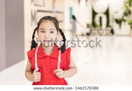 The cute little Asian girl smiled happily in the mall.