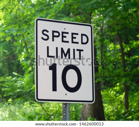 A close view on the speed limit sign with the green leaves of the trees as the background.