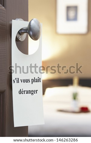 Sign with French text "s'il vous plait deranger" (please disturb) hanging on hotel room door