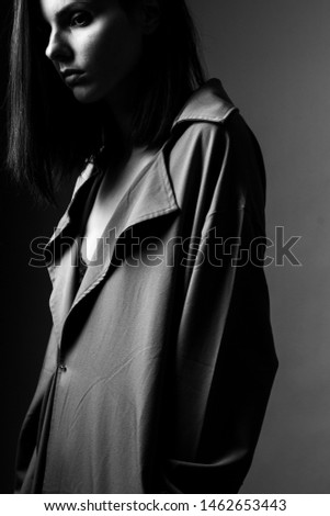 beautiful young girl in a trench coat, black and white vertical photo