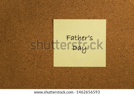 Small yellow sticky note on an office cork bulletin board. "Fathers Day"