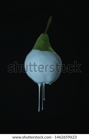 Beautiful fresh pear dripping white paint on  a black background. Creative poster.