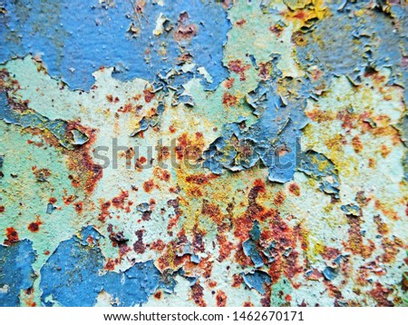 abstract view of a blue rusty and weathered metal plate with peeling paint.