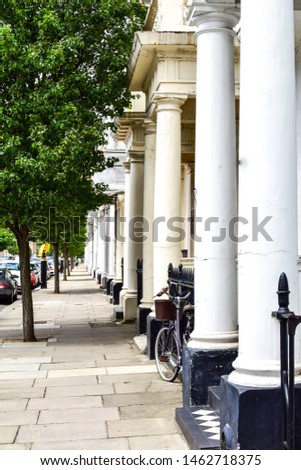 View of street in the fashionable neighborhood of Pimlico. Traditional white townhouses with impressive white pillars out front-Image