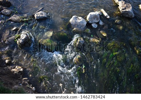Moving cold water down between stones and some rubbish in the river