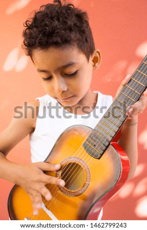 Adorable Hispanic boy playing guitar Royalty-Free Stock Photo #1462799243
