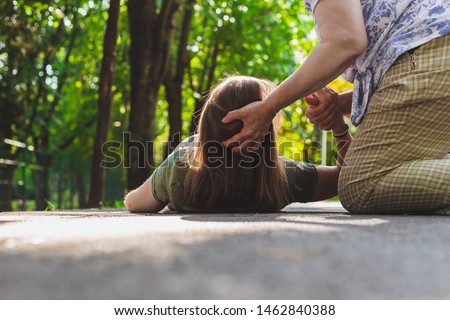 Fainted girl helped by an old woman – Teenager trying to get back on her feet while receiving support from an elder Royalty-Free Stock Photo #1462840388