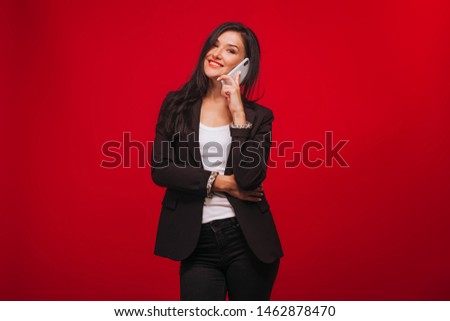 girl in a business suit talking on the phone. On red background