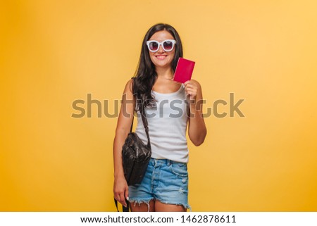Girl tourist on a yellow background with a backpack and a passport