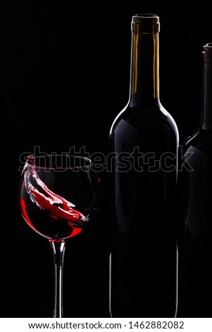 From a glass of wine splashing next to the bottle on a black background.