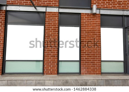 Billboard shop window with glass, against a brick wall.