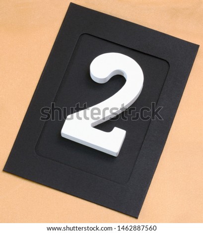 Wooden white number two in photo frame on a gold background. Greeting card harvesting for Christmas.
