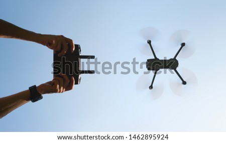 Remote control in men hands and the silhouette of a flying drone. View from the bottom