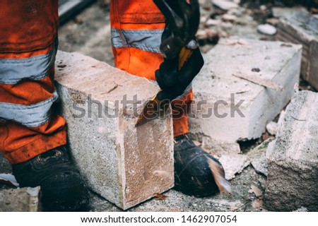 damage wall repaired by builders cleaning stone and blocks with hammer and chisel wearing hi vis trousers 