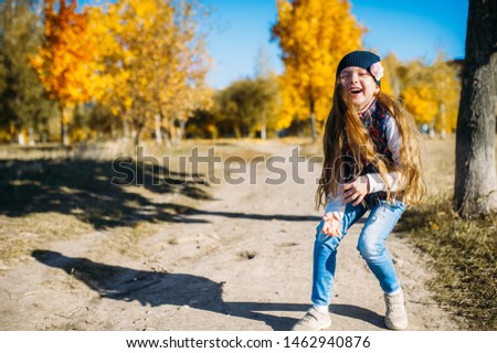 Portrait of a cheerful girl in a hat with a flower laughing among the autumn trees