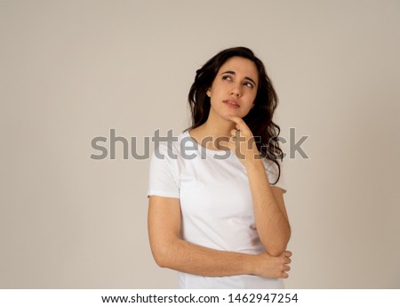 Portrait of happy charming latin young woman with long black hair thinking new ideas or planning future, birthday surprise wandering how to do it. Teenager with thoughtful facial expression.