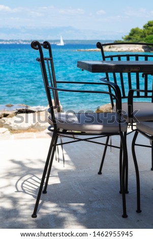 Vacant chair and table at the bar next to the beach on Croatian island Ugljan. Summer, vacation, travel, luxury and relaxation concepts.