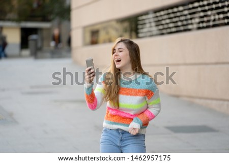 Pretty teenager woman happy and excited on smart mobile phone checking surprised lots of likes and followers on her blog. Urban background. In technology Communications online Trends and Blogging.